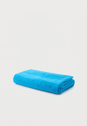 Bright blue folded towel with textured fabric and towel band detail on a plain white background.