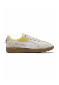Lys beige sneakers med hvide og gule detaljer, struktureret ruskind og lædermaterialer, flad gummisål og lille logo-detalje på hælen.