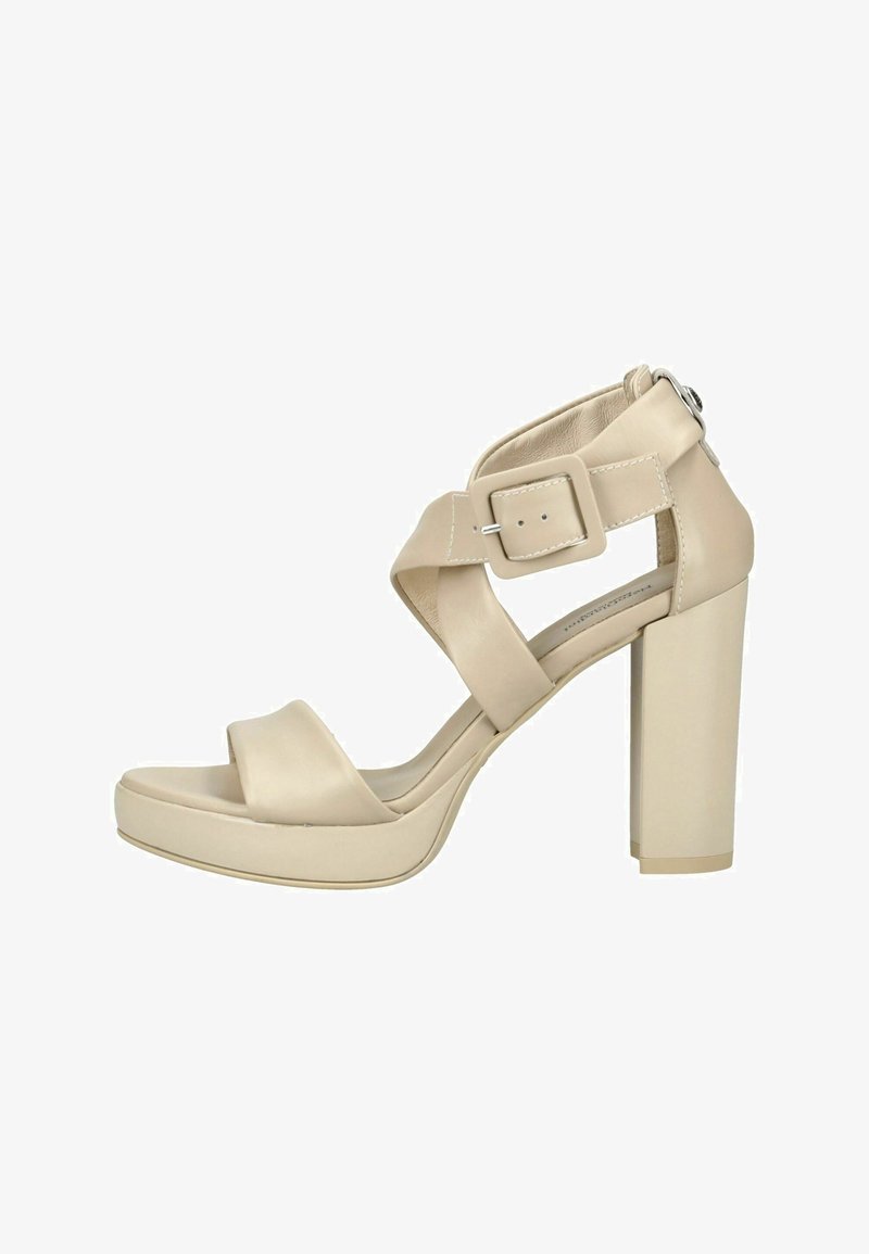 Sandale beige à talon haut avec larges lanières croisées, grande fermeture à boucle et talon bloc épais sur fond blanc.