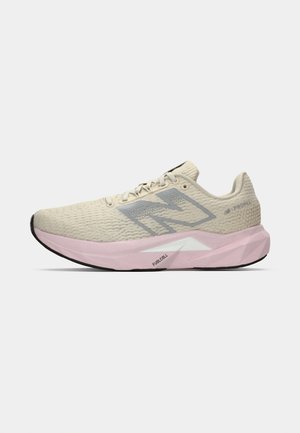 Zapatilla de running en beige claro con logo gris "N", suela rosa etiquetada como "FuelCell" y talón texturizado, presentada sobre un fondo blanco.