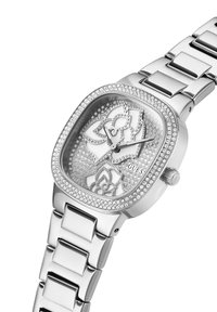 Reloj rectangular plateado con embellecimientos de cristal, patrón floral en la esfera y una pulsera de eslabones de acero inoxidable.
