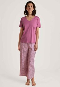 Roze V-hals t-shirt van zachte stof, gecombineerd met brede pyjamabroek met een klein bloemmotief in tinten van roze en wit.