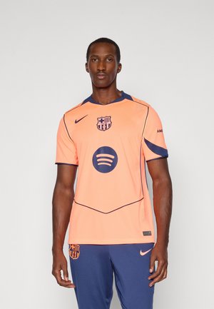 Peach athletic jersey with navy accents and logo, featuring short sleeves, crew neck, and textured material; includes Spotify logo at center.