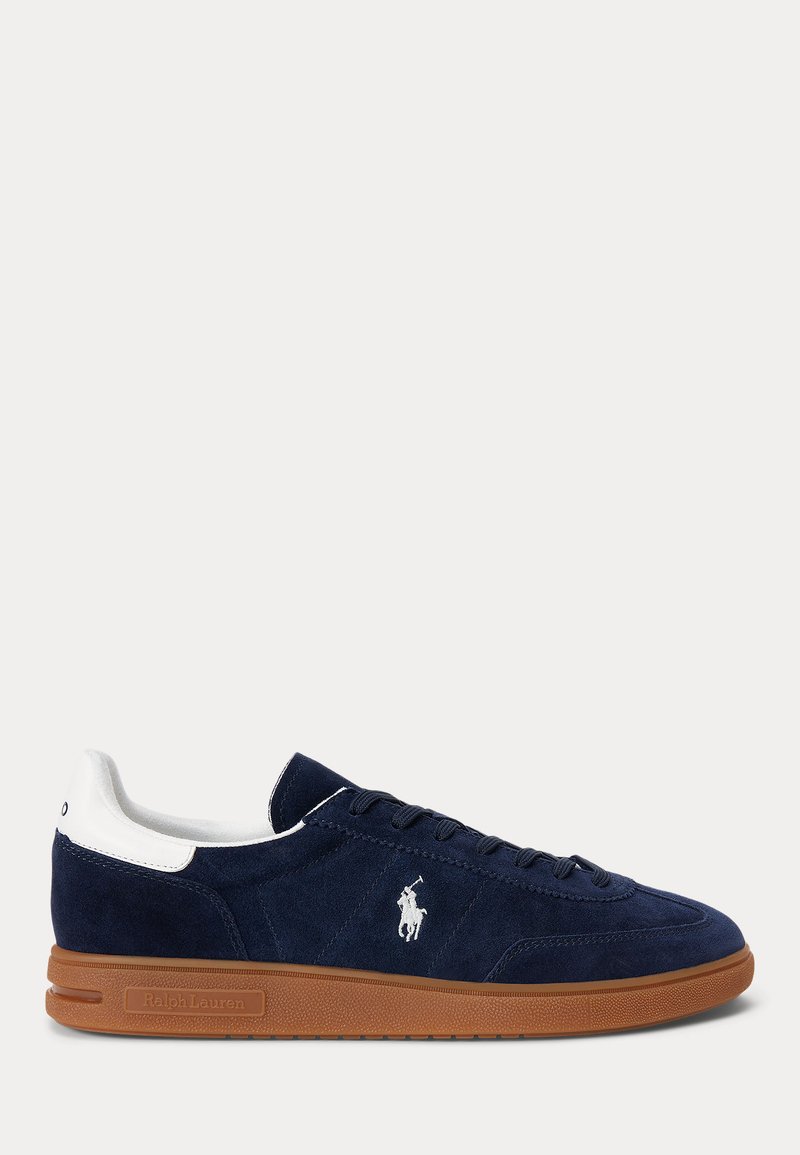 Sneaker in camoscio blu navy con linguetta bianca sul tallone, logo ricamato sul lato, suola in gomma marrone e lacci neri.