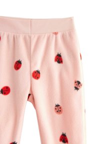 Fleece pyjamasbukser i lys pink med et mønster af røde og sorte mariehøns. Elastisk talje, blød tekstur og ingen lommer.