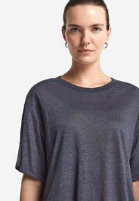 Mörkgrå t-shirt med kort ärm, avslappnad passform och rund halsringning. Mjuk, lätt tyg med en subtil textur. Minimalistisk design.