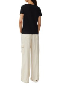 Zwarte korte mouwen t-shirt met een ronde hals, gecombineerd met losse beige cargo broek met zijzakken en een gestructureerde stof.