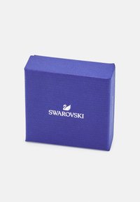 Mėlynas tekst�ūruotas dovanų dėžutė su baltu "Swarovski" logotipu, turinti gulbės dizainą. Stačiakampio formos su lygiomis briaunomis.