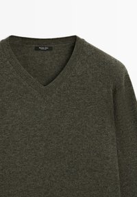 Pull en maille vert foncé à col en V avec col côtelé, étiquette indiquant "Massimo Dutti Fabriqué en Chine."