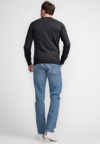 Pulover navy cu guler rotund, asortat cu blugi de culoare albastru deschis. Ținuta are un design simplu și clasic și este purtată cu adidași albi.