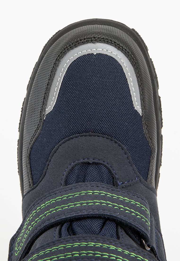 Marineblaue Schuhe mit grauen Akzenten und grüner Naht. Merkmale eine runde Zehenpartie und zwei verstellbare Klettverschlüsse. Texturiertes Gewebe und Gummisohle.