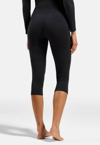 Schwarze 3/4-Leggings mit strukturiertem Rippdesign, ausgestattet mit einem hohen Taillenbund und Akzentpaneelen, die entlang der Beine verlaufen.