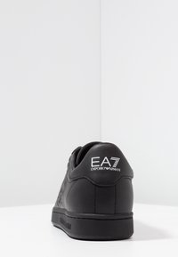 Svarta lädersneakers med en texturerad sidodesign, platt gummisulor och präglad logotyp på hälen. Minimalistisk och strukturerad form.