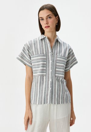 Camicia a righe con bottoni in tessuto leggero; presenta maniche corte, due tasche anteriori e righe alternanti blu, grigie e rosa.
