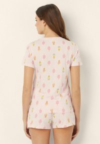 Conjunto de pijama de manga corta en color rosa con patrones de conos de helado y polos. Tela suave con un ajuste cómodo, diseñado para la relajación.