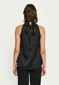 Top halter din satin negru, cu un guler pliat și o fundă mare în spate. Textură netedă, cu o croială lejeră și un tiv curbat.