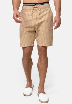 Beige stribede shorts med snøre i livet, to forlommer og en afslappet pasform. Sammen med hvide slip-on sko.