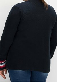 Cardigan a maglia blu navy scuro con trama a coste, caratterizzato da un motivo a zigzag multicolore sulle maniche e una vestibilità lunga e rilassata.