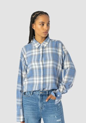 Blue and white plaid button-up shirt with long sleeves, paired with distressed blue jeans. Features a classic collar and relaxed fit.