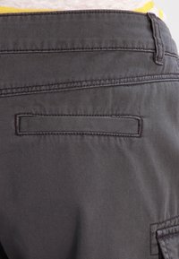 Ciemnoszare spodnie casual o gładkiej strukturze, z tylną kieszenią z poziomym rozcięciem i subtelnymi detalami szwów.