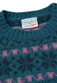 Pletený svetr v tyrkysové barvě se vzory cikcak v růžové a šedé. Žebrovaný výstřih a lem. Štítek nese nápis "benetton, curated by Amy Paris."