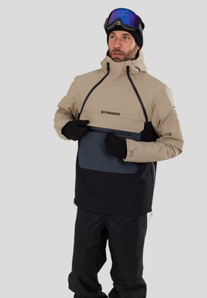 Beige und schwarze wasserdichte Jacke mit einer Vorderertasche, verstellbarem Kapuzen, und grauen Akzenten, kombiniert mit schwarzen Schneehosen und Handschuhen.