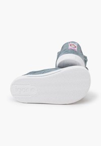 Baskets montantes grises avec une semelle blanche, ornées d'une étiquette colorée qui indique "Fabriqué en Espagne" à l'arrière. Les chaussures sont positionnées debout.