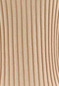 Beige geripptes Gewebe mit vertikalen Streifen, das eine weiche Textur und ein konsistentes Muster aufweist. Eignet sich für verschiedene Bekleidungsanwendungen.