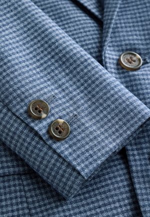 Niebieska, kraciasta tkanina rękawa koszuli z dwoma brązowymi guzikami. Tekstura jest tkana z subtelnym wzorem kratki.