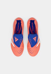 Zapatillas deportivas de slip-on en naranja y azul con un upper texturizado, acentos blancos y un diseño deportivo que presenta un logotipo y detalles de patrón.