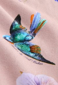 Lyserødt stof med et detaljeret tryk af en farverig fugl, der fremviser levende blå, grønne og orange nuancer, med blomsterdetaljer synlige.