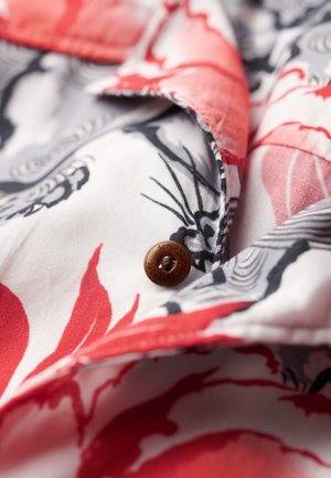 Rode en zwarte bloemmotief stofshirt met een bruine knop met de gegraveerde tekst "SUPERDRY" en een gestructureerde rand.
