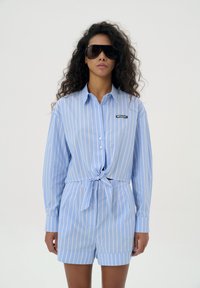 Blauw en wit gestreepte shirt met een vest voor, knoopsluiting en branding; gecombineerd met bijpassende shorts, heeft een ontspannen pasvorm.