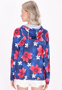 Blommig huva jacka med blå bakgrund och stora röda hibiskus- och vita blommönster; lättviktig, med en avslappnad passform och långa ärmar.