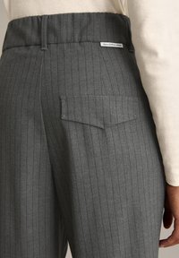 Grijze pinstriped broek met een hoge elastische tailleband, voorzien van een achterzakdetail en een klein merkembleem op de achterkant.