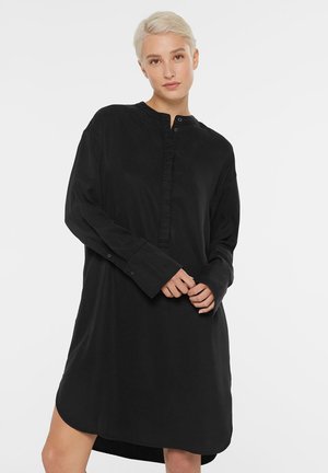 Schwarzes Langarmkleid mit einem knöpfbaren Kragen, hergestellt aus weichem Stoff. Verfügt über einen lockeren Schnitt und einen geschwungenen Saum.