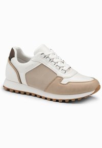 Baskets de sport blanches et beige avec un panneau latéral texturé, fermeture à lacets, semelle rembourrée et semelle extérieure en caoutchouc antidérapante.