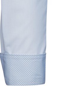 Camicia azzurro chiaro con strisce verticali, caratterizzata da un polsino a pois blu e bianchi a contrasto. Tessuto in cotone con una texture liscia.