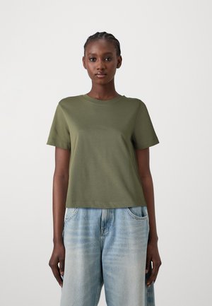 Camiseta de manga corta color verde oliva hecha de material suave, con cuello redondo y corte relajado, combinada con jeans de pierna ancha color azul claro.