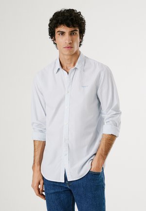 Camicia button-up a righe di colore azzurro chiaro con colletto. Tessuto morbido, maniche lunghe arrotolate ai polsini. Dettaglio del logo blu sulla tasca del petto.