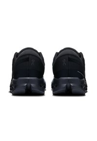 Chaussures de sport noires dotées d'un dessus en mesh texturé, de talons rembourrés et d'une semelle en caoutchouc léger avec des éléments de amortissement uniques.