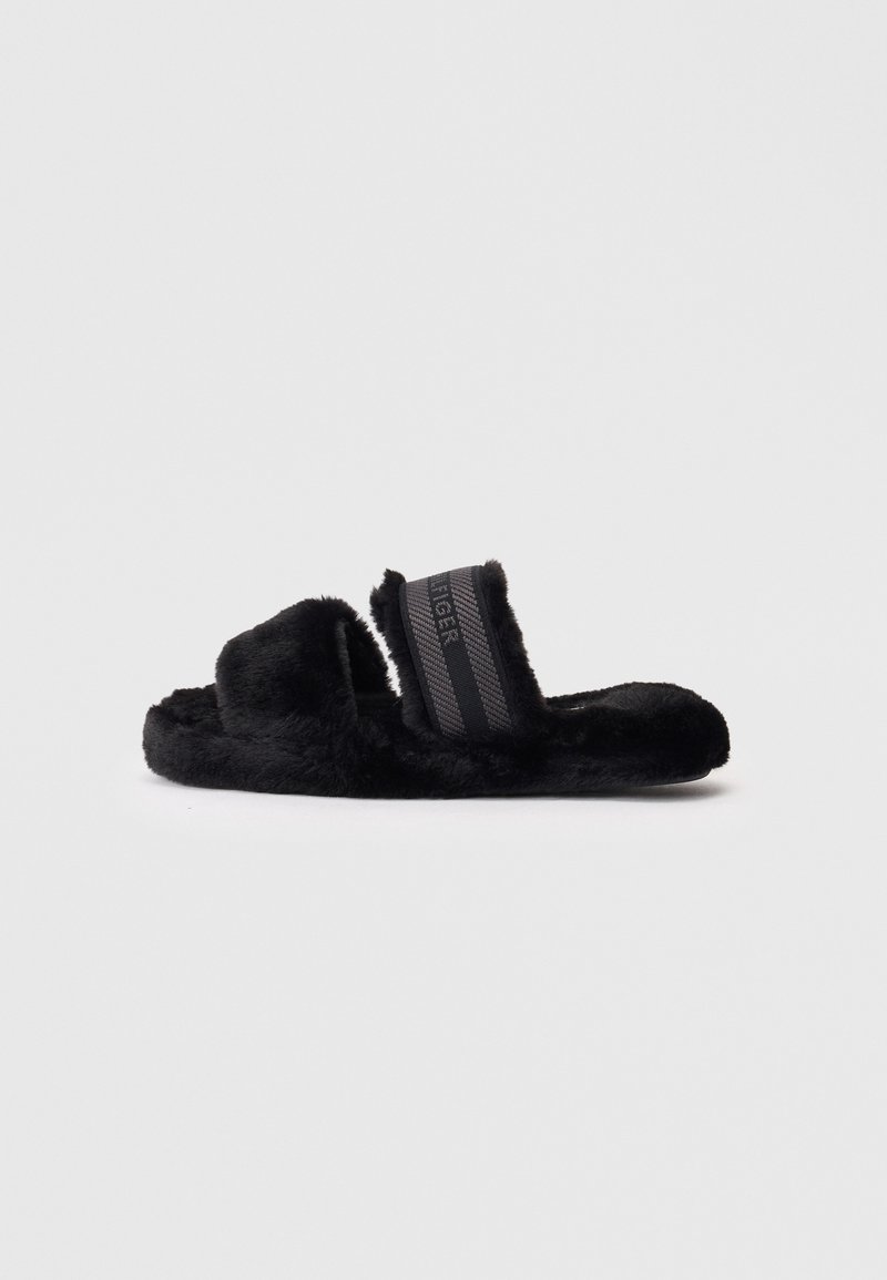 Schwarze Fleece-Pantoletten mit weicher Textur, zwei breiten Riemen und einem kontrastierenden schwarz-gestreiften Design auf dem Riemen. Flache Sohle für Komfort.