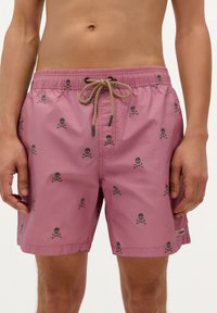 Pantaloni scurți de baie roz, realizați dintr-un material ușor, având un model cu craniu și oase încrucișate negre, un șnur reglabil și buzunare laterale.