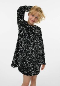 Mustmust särgiga must kleit pikka varrukatega, laia lõike ja ümarate kaelustega. Läikivad sequins katavad kogu pinna, peegeldades valgust.