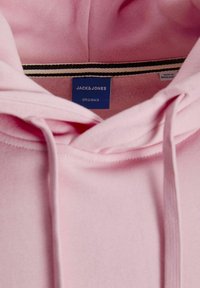 Rosa hættetrøje med snor, blød tekstur og en blå label med "JACK & JONES ORIGINALS." Sort og hvid stribet indvendig krave.