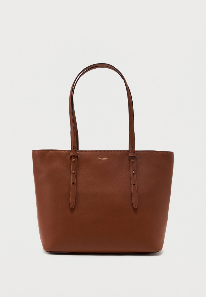 Sac cabas en cuir marron avec deux fines bretelles réglables et petit logo doré en texte au centre supérieur devant.
