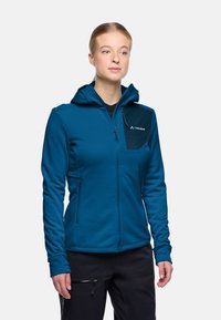Giacca zip-up color teal con cappuccio. Caratterizzata da una tasca sul petto nera e tasche laterali con zip. Tessuto morbido con costruzione resistente.