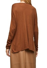 Pull marron surdimensionné avec manches longues, texture douce et encolure dégagée, doté d'un ourlet asymétrique et de poignets côtelés.