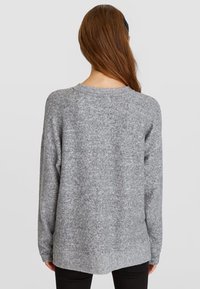 Grå strikket sweater med en let løs pasform, rund halsudskæring og lange ærmer. Struktureret stof med et subtilt mønster.