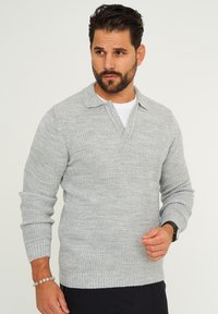 Hellgrauer gestrickter Pullover mit Kragen, langen Ärmeln, gerippten Bündchen und einem strukturierten Muster. Lockerer Sitz.